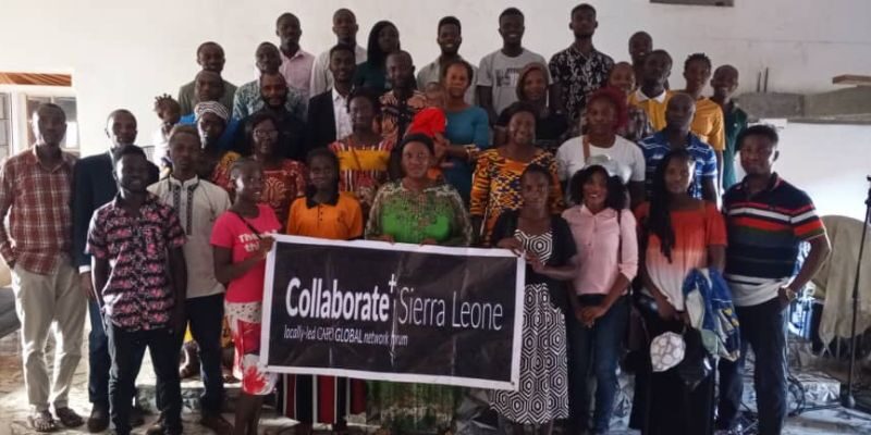 leaders in Sierra Leone at Collaborate event smiling holding a sign